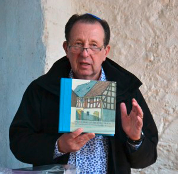 Jeffrey Streimer, Nachfahre der Familie Strauß aus Obertiefenbach, präsentierte in der ehemaligen Synagoge eine Familienchronik mit dem Bild des ehemaligen Wohnhauses der Familie.